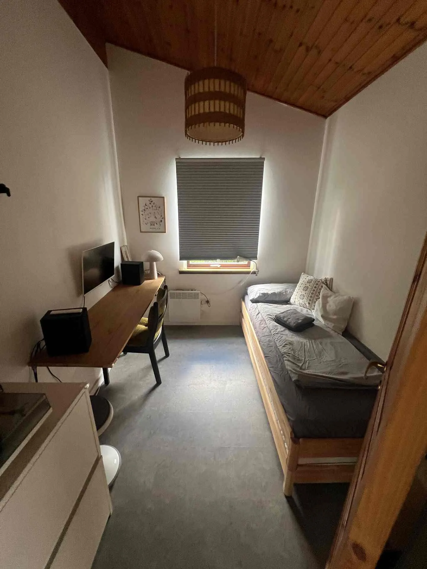 Kleines Arbeitszimmer mit Schreibtisch, Monitor und Stuhl, daneben ein Tagesbett am Fenster